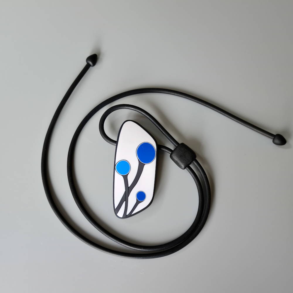 Handmade shield shaped necklace featuring an abstract flower bud motif in blue on a white background, with charcoal border. It is approximately 2.6 cm wide and 6.4cm long and hangs on a black adjustable cord.